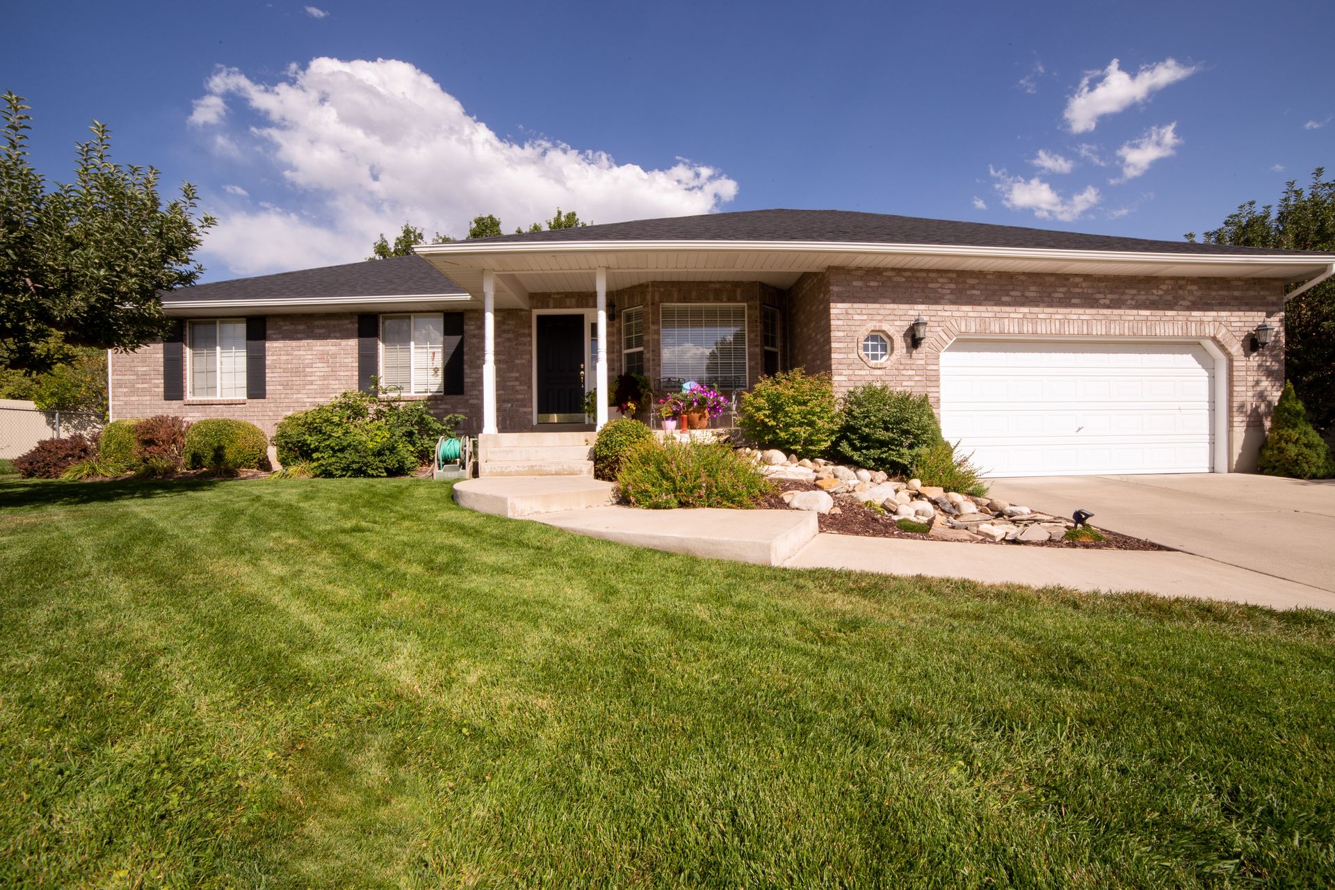 A modern suburban house exterior with a beautiful landscaped yard on a sunny day.
